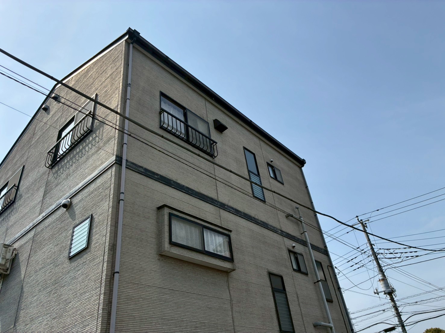 古びた外壁の3階建て住宅を見上げる
